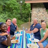 6 GVSU Alumni sit together and smile on a John Ball Zoo picnic table